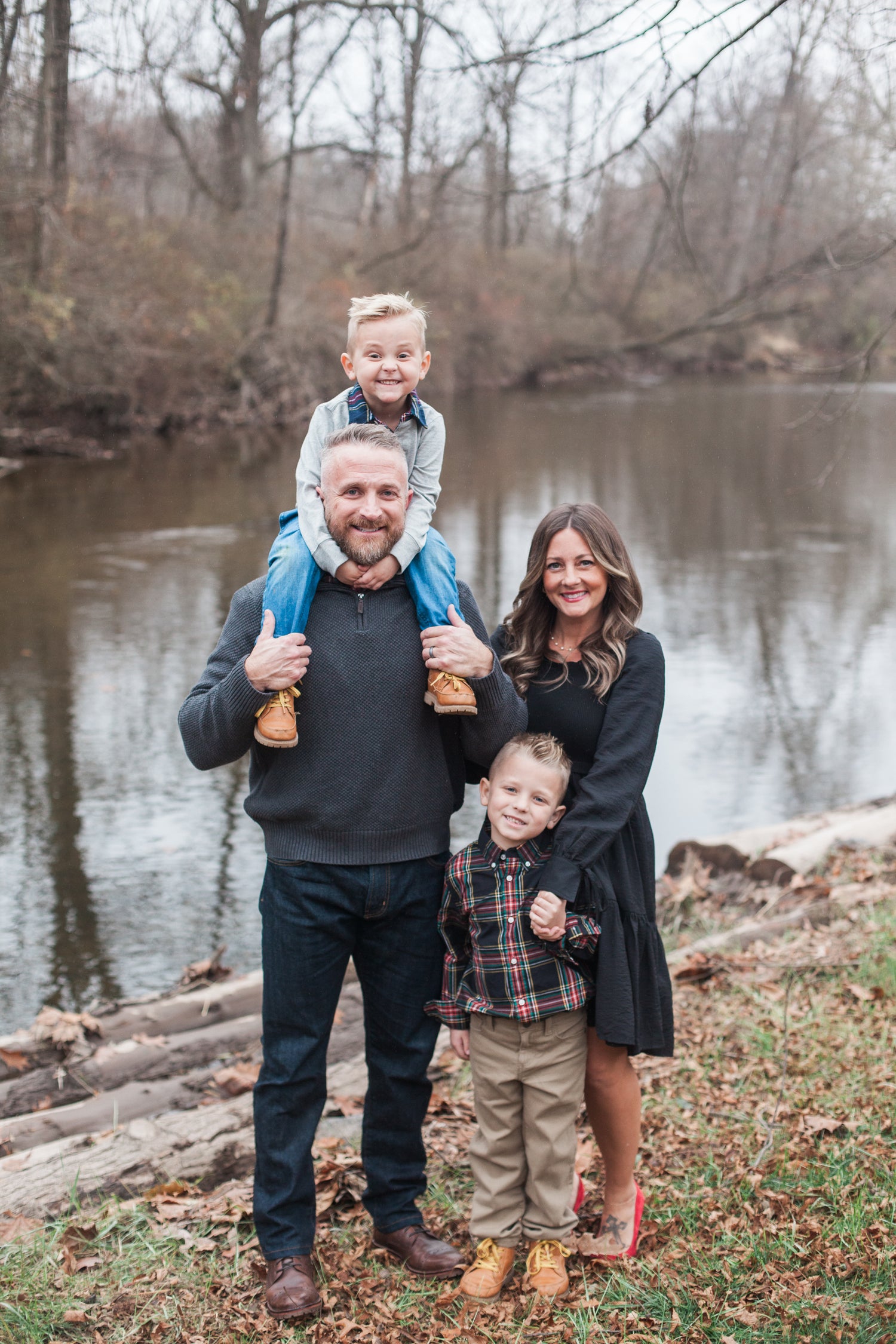 a family photo of a mother, father, and two young boys dressed nicely and standing beside a creek